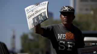 Newspaper vendor in Mexico City holds up newspaper that reads Obama Wins