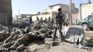 An Afghan policeman stands guard at the scene of a suicide attack in Kandahar, south of Kabul, Afghanistan, Thursday, Nov. 8, 2012.