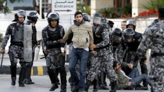 Jordanian policemen detain protesters blocking a main road during a demonstration against a rise in fuel prices in downtown Amman on 14 November