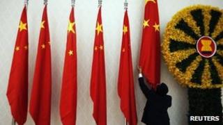 An official adjusts Chinese flags before Chinese Premier Wen Jiabao arrives for the 21st Asean and East Asia summits in Phnom Penh, 18 Nov 2012