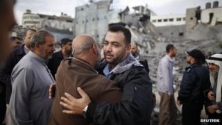 A Hamas police officer is hugged by a Palestinian man after they returned to their destroyed police headquarters in Gaza City November 22, 2012