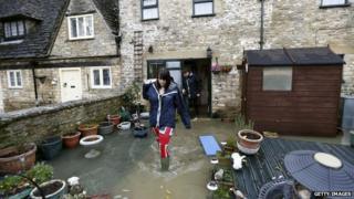 People walking out of their home into a flooded garden