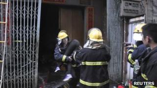 Fire fighters carry a victim of the Shantou city blaze