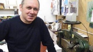 Bookbinder Tom McEwan in front of a massive guillotine