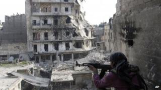a Free Syrian Army fighter is in position in front of destroyed buildings in Aleppo, Syria on 29 November