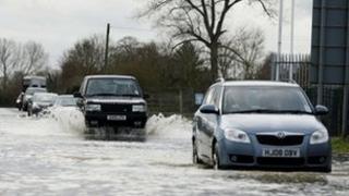 People drive along a flooded road near Melksham in Wiltshire