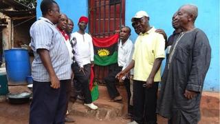 Мужчины поют гимн рядом с флагом Биафрана