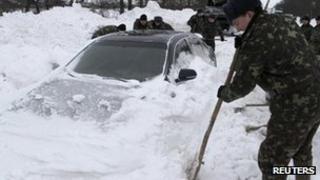 Emergency workers dig out a car trapped in snow in western Ukraine. Photo: December 2012