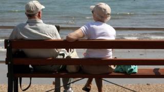 Elderly couple sitting on bench on sea front