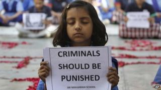 Индийская школьница держит плакат во время молитвенной церемонии, чтобы оплакать смерть 23-летней жертвы группового изнасилования, в школе в Ахмадабаде, Индия, в субботу, 29 декабря 2012 года.