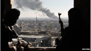 Free Syrian Army fighters watch smoke rising from buildings from their position during a fight with forces loyal to Syrian President Bashar al Assad at the front line in Aleppo December 26