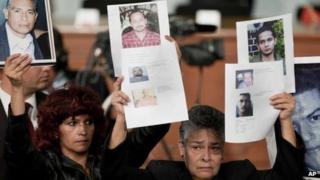 People hold up photographs of alleged victims of crime during an event at which President Pena Nieto enacted the crime victims law