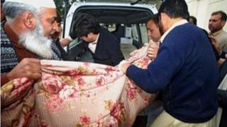 Police place the dead body of the officer into a van on 18 January 2012
