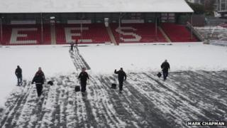 Football fans help clear snow from Griffin Park pitch - BBC News