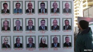 A man looks at electoral posters for parliamentary candidates in Amman January 20, 2013