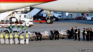 Officers bow their heads as they place flower bouquets on coffins of Algerian hostage crisis victims
