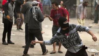 An Egyptian protester throws a stone at police in Tahrir Square in Cairo