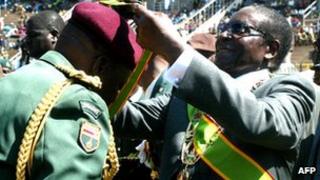 Zimbabwean President Robert Mugabe (R) confers the medal of honour to an army officer at the National Sports Stadium in Harare on 9 August 2011