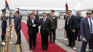 Mahmoud Ahmadinejad (L) and Mohammed Morsi (R) stand together at Cairo International Airport (5 February 2013)