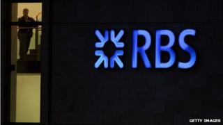 RBS employee looks out from the headquarters building next to a neon sign