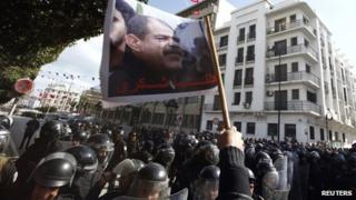 Tunisian protesters shout slogans during a demonstration after the death of opposition leader Chokri Belaid (pictured on flag), outside the Interior ministry in Tunis on Wednesday 6 February 2013