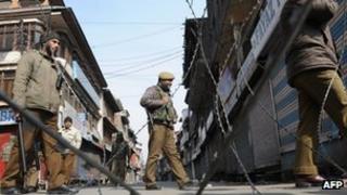 Indian police patrol a deserted street in Srinagar