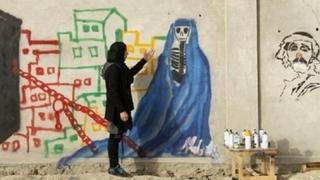 Malina Suliman in front of her drawing of a skeleton in a burka