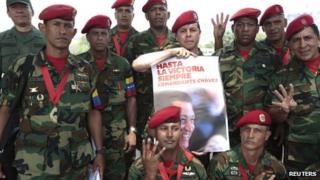 Soldiers of the military group 4F pose for a photo with a poster of Hugo Chavez outside the Military Academy, where the funeral service of Mr Chavez is being held, in Caracas on 10 March 2013