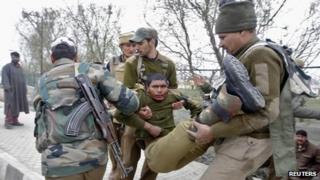 Indian paramilitary soldiers carry an injured colleague to a hospital during a fight in Srinagar on March 13, 2013