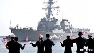 Управляемый ракетный эсминец USS Lassen (DDG 82) прибывает, когда моряки ВМС Южной Кореи развевают флаги Южной Кореи и США в военно-морском порту Южной Кореи в Донхэ, примерно в 190 км (118 милях) к востоку от Сеула, 9 марта 2013 г.