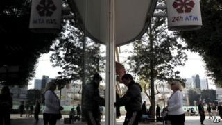 A young man receives money from an ATM machines outside a closed Laiki Bank branch in capital Nicosia,