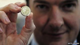 George Osborne holding up a pound coin
