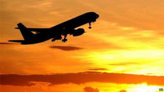 A plane flying towards the sunset