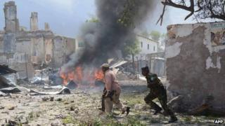 Somali police run after a suicide attack in Mogadishu on 14 April 2013