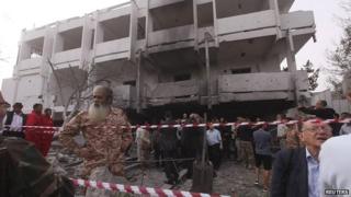 People stand among debris outside the French embassy after the building was attacked in Tripoli, 23 April 2013