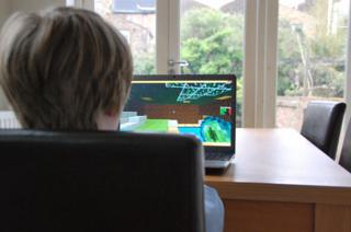 Un garçon joue avec Minecraft à la table de la cuisine