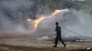 A firefighter runs towards a burning stock of hay which belongs to a Muslim household in Oakkan, 30 April 2013