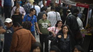 Люди идут по многолюдной улице в Мехико