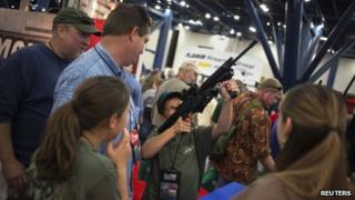 Family members watch as 11-year-old Mark takes aim with an AR-15 style assault rifle on the exhibit floor at the NRA annual meeting in Houston, Texas, on 3 May 2013