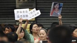 This picture taken on 8 May 2013 shows protesters holding banners and a photo of a young woman who fell to her death at a wholesale clothing centre in Beijing