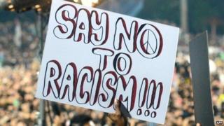 A fan holds a sign saying 'say no to racism' at a match