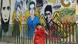 A young boy walks past graffiti images of those killed in the revolution in Tahrir Square
