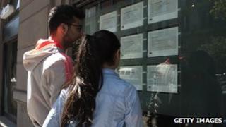 Two people look at job announcements on the window of an agency in Naples