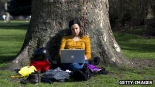 woman sitting under a tree on her laptop