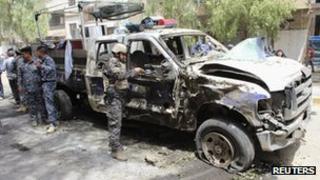 Iraqi security personnel inspect the site of a bomb attack in a district of Baghdad