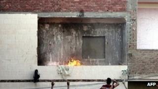 Egyptians look on as a mob attacks Shia Muslim men gathered in a house