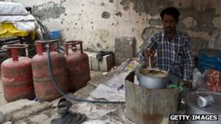 A roadside teashop owner makes tea next to LPG cylinders in New Delhi.