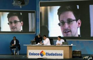 Ecuadorean President Rafael Correa speaks on a TV programme in El Aromo, Manabi, in front of giant screens showing Edward Snowden, 29 June