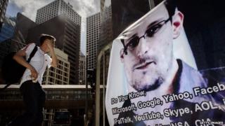 Man walking by a poster of Edward Snowden in Hong Kong
