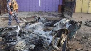 Policeman walks past car destroyed in Kirkuk attack (11/07/13)